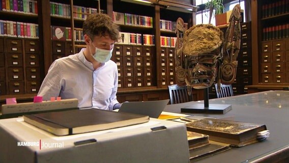 Jamie Dau beschäftigt sich intensiv mit einer historischen Maske aus Papua Neuguinea im MARKK Museum Hamburg  