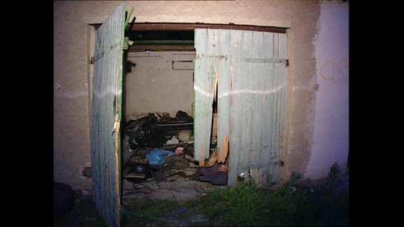 Eine vermüllte Garage bei Dunkelheit  