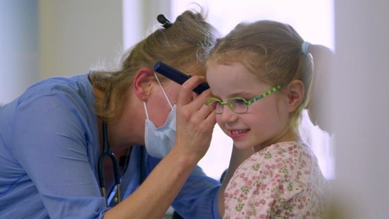 Eine Kinderärztin untersucht ein Mädchen.  