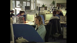 Mitarbeiter eines Callcenters sitzen an Computern  