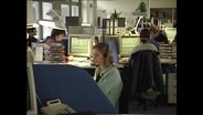 Mitarbeiter eines Callcenters sitzen an Computern  