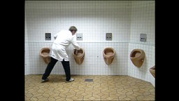 Ein Mann putzt Toiletten  