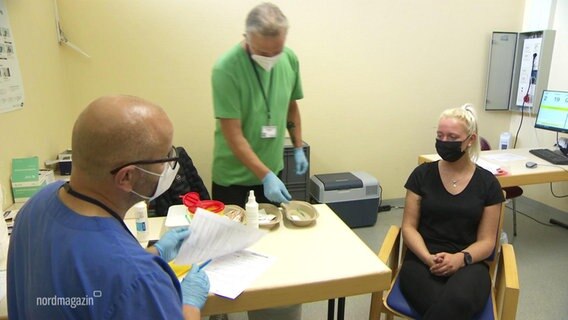 Eine Patientin und zwei Mitarbeiter im Schweriner Impfzentrum  