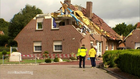 Blick auf ein zweistöckiges Familienhaus, dessen oberste Etage komplett zerstört ist.  