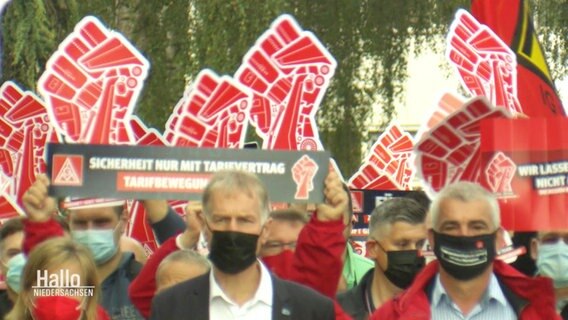 Blick über eine Menge von demonstrierenden Menschen, die zum Teil Transparente einer roten Faust in die Luft strecken.  