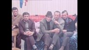 Fünf Gastarbeiter sitzen auf einem Sofa  