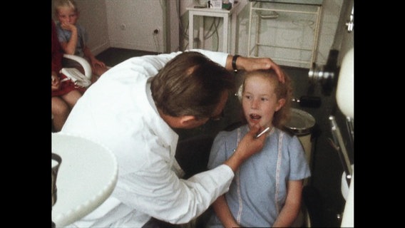 Ein Kieferorthopäde untersucht eine junge Patientin  