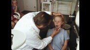 Ein Kieferorthopäde untersucht eine junge Patientin  