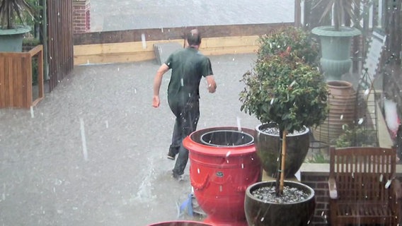 Ein Mann läuft bei Regen durch Hochwasser  