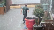 Ein Mann läuft bei Regen durch Hochwasser  