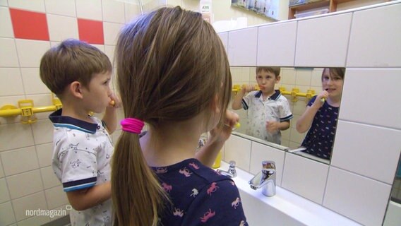 Zwei Kinder putzen sich die Zähne in einer Kita.  