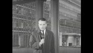 Werner Baecker spricht in ein Mikrofon  