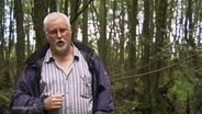 Der Wissenschaftler Hans Jossten gibt ein Interview in einem Wald.  
