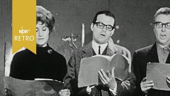 Zwei Schauspieler und eine Schauspielerin lesen aus dem Skript bei einer Theaterprobe (1965)  