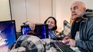 Ein Ehepaar im Bett wärmt sich am Computer.  