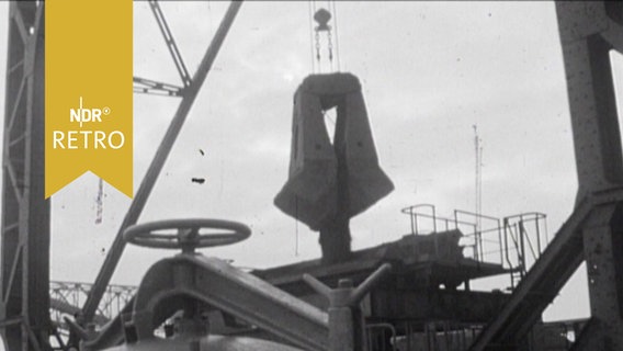 Erz fällt aus einer Kranschaufel auf ein Förderband im Emder Erzhafen 1963  