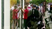 Eine Polizeistreife kontrolliert einen jungen Mann.  