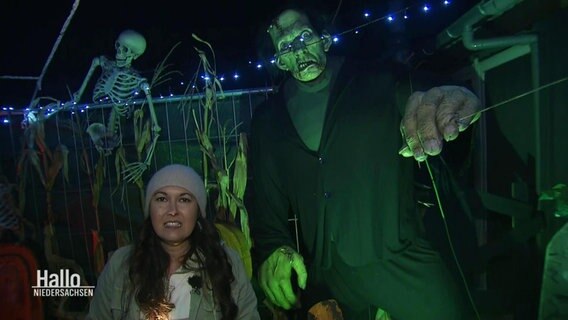 Reporterin Vanessa Kossen steht neben einer übergroßen und grün angeleuchteten Figut von Frankensteins Monster.  