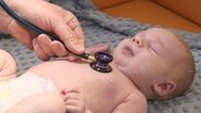Ein Baby wird von einem Arzt untersucht.  