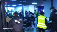 Mehrere Polizeibeamte stehen in einem Haus bei einer Razzia.  