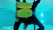 Ein Kind schnorchelnd unter Wasser mit einer VR-Brille.  