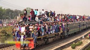 Menschen auf einem überfüllten Zug in Indien.  