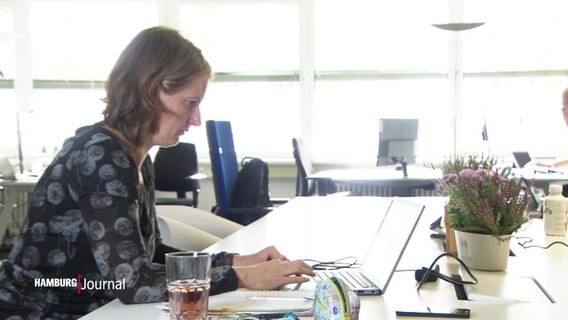 Eine Frau sitzt an einem Schreibtisch in einem Coworking Space  