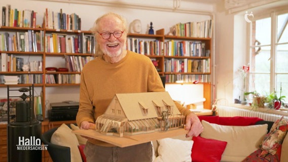 Declan Kennedy hält ein Modell von einem Haus in seinen Händen.  