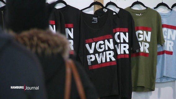 Mehrere T-Shirts hängen nebeneinander, sie tragen alle die Aufschrift "VGN PWR", als Abkürzung für Vegan Power.  