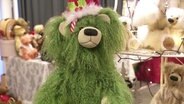 Ein grüner Teddybär vor vielen anderen Teddybären  