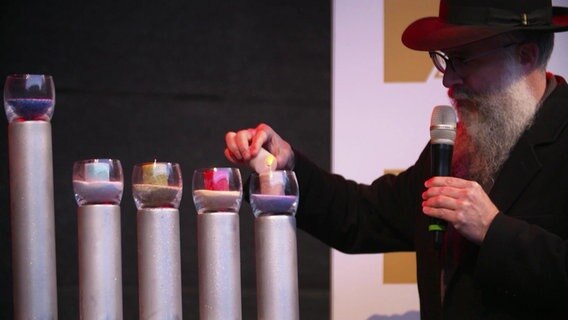 Landesrabbiner Shlomo Bistritzky zündet Kerzen an einer Menora an  