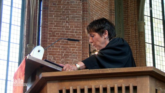 Margot Käßmann spricht an einer Kirche.  