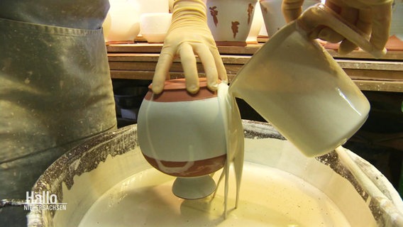 In einer Töpferei wird eine Vase bearbeitet.  