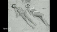 Schwarz-weiß-Foto von Frauen am Strand.  