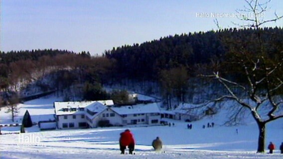 Eine Archivaufnahme von 1996. Zwei Menschen rodelt oder fahren mit Ski den Dörenberg in Niedersachsen herunter.  