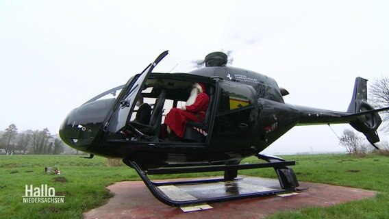 Ein als Nikolaus verkleideter Mann sitzt in einem Hubschrauber.  