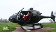 Ein als Nikolaus verkleideter Mann sitzt in einem Hubschrauber.  
