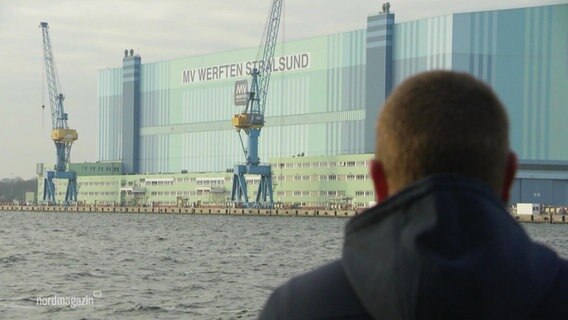 Ein Mann blickt auf die MV Werften.  