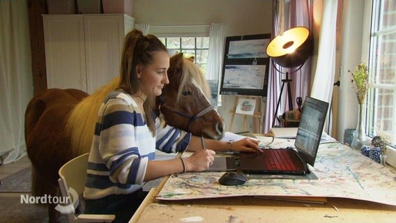 Imke Hahn sitzt mit Pferd am Schreibtisch. © Screenshot 