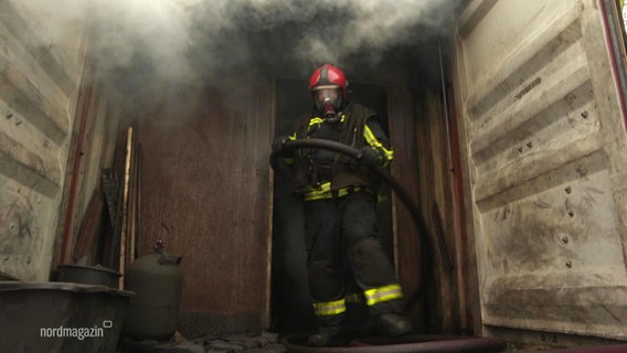 Ein Feuerwehrmann kommt aus einem qualmenden Übungscontainer. © Screenshot 