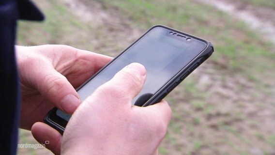 Ein Smartphone ist zu sehen, im Hintergrund ein Acker. © Screenshot 