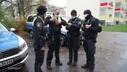 Ein Team der Stralsunder Polizei bespricht sich draußen. © Screenshot 
