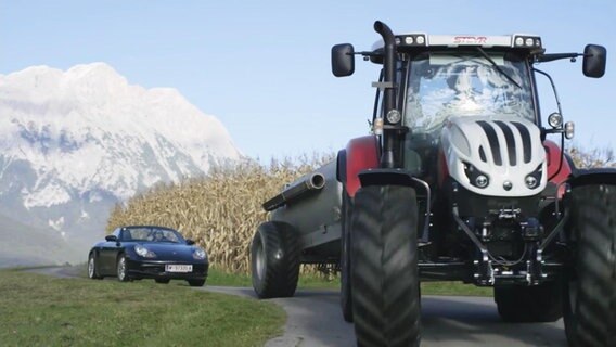 Ein Porsche fährt hinter einem Traktor und kommt nicht vorbei. Szene aus einer Werbung. © Screenshot 