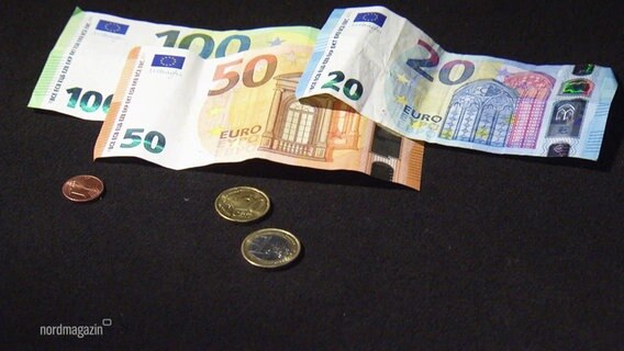 Mehrere Euroscheine und einige Euromünzen liegen auf einem schwarzen Untergrund. © Screenshot 
