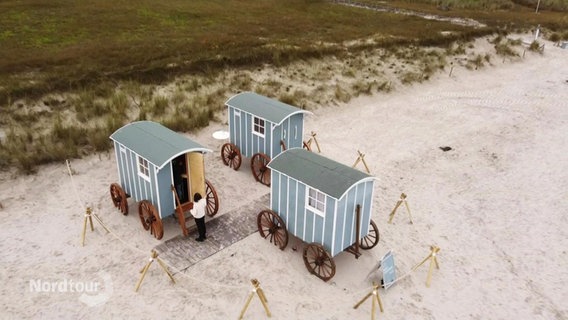 Drei Saunawagen stehen am Strand. © Screenshot 