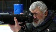 Rainer Kuschnierzik mit einer Fotokamera. © Screenshot 