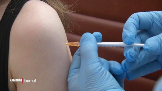 Eine Impfspritze wird in einen Arm injiziert. © Screenshot 