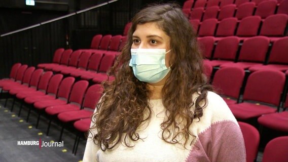 Eine junge Frau steht im Zuschauerraum eines Theaters und gibt ein Interview. © Screenshot 