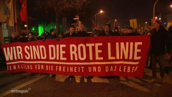 Demonstrierende gegen Corona-Maßnahmen mit einem großen Banner mit der Aufschrift "Wir sind die rote Linie - Gewaltlos für die Freiheit und das Leben." © Screenshot 