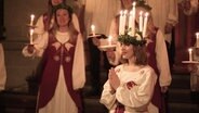 Lucia trägt einen Kranz mit Kerzen beim Luciafest in einer schwedischen Kirche. © Screenshot 